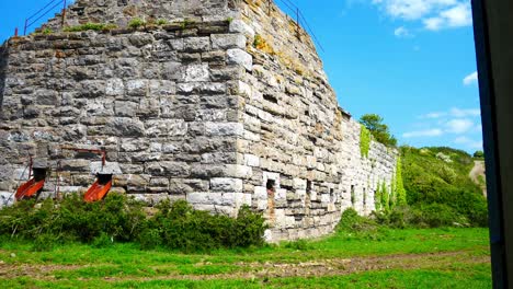 Old-abandoned-landmark-stone-mill-restoration-buildings-on-Welsh-industrial-coastal-countryside-dolly-right