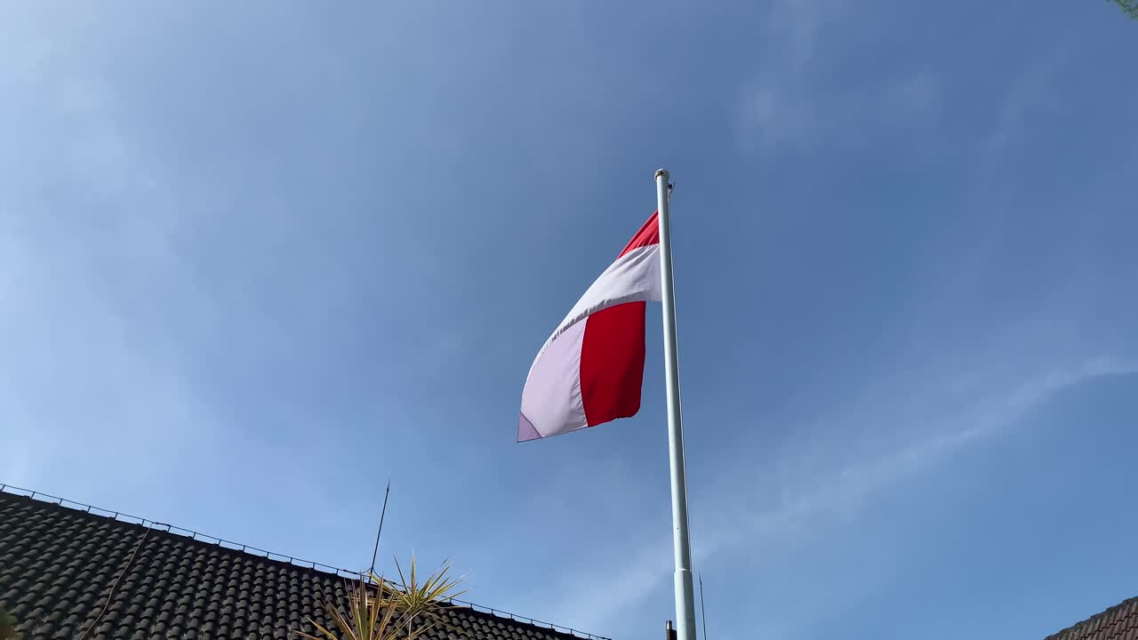 인도네시아 국기 는 사무실 구역 에서 아름다운 파란 하늘 을 배경 으로 높은 기둥 에 날아다니고 있다