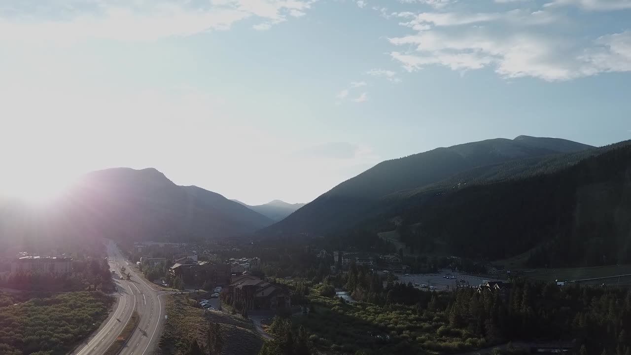 Aerial shot pushing towards the mountains as sunbeams break across the summit
