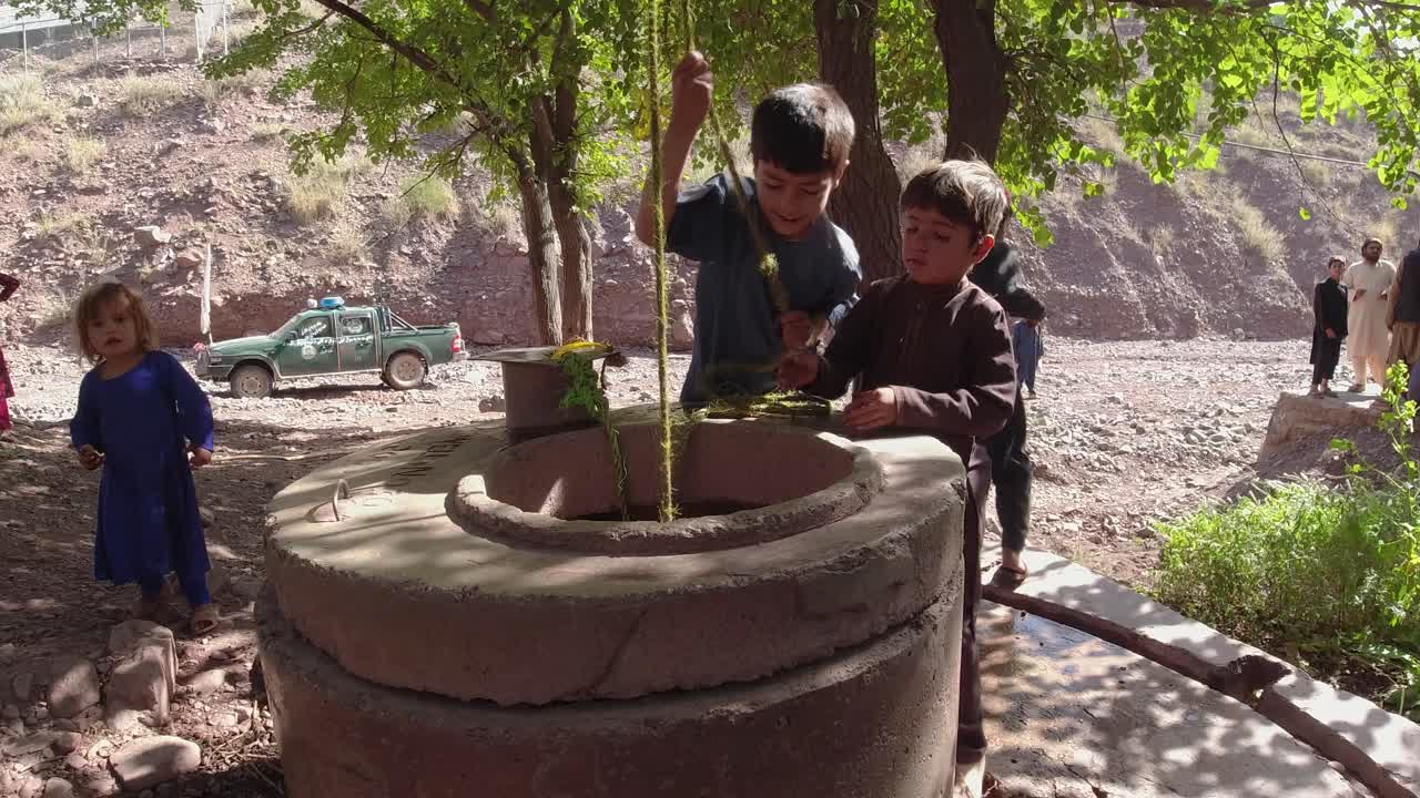 un joven usando sus manos para recoger agua de un pozo