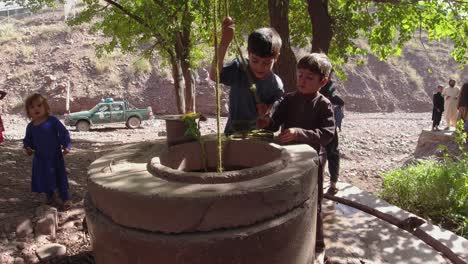 a youngster using their hands to gather water from a well