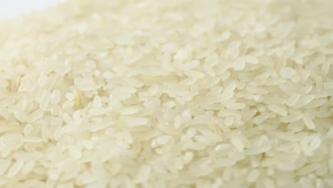 macro white raw rice texture, food background, vegetarian healthy eating product. rotating close up of a pile of raw rice