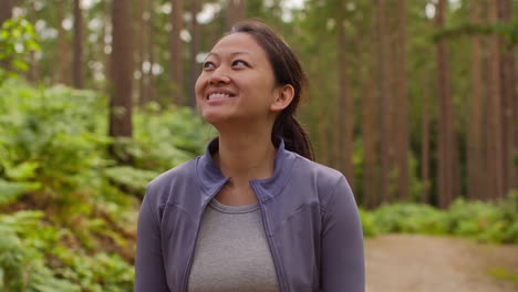 mujer con ropa deportiva haciendo ejercicio mirando a su alrededor caminando por una pista en el bosque disfrutando de la paz y la belleza de la naturaleza 1