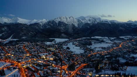 illuminated zakopane city in the evening of winter in poland - aerial shot