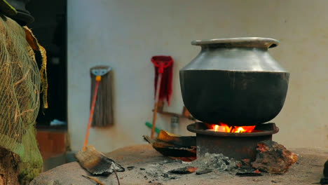 a aluminium pot is placed on a traditional fireplace with burned woods