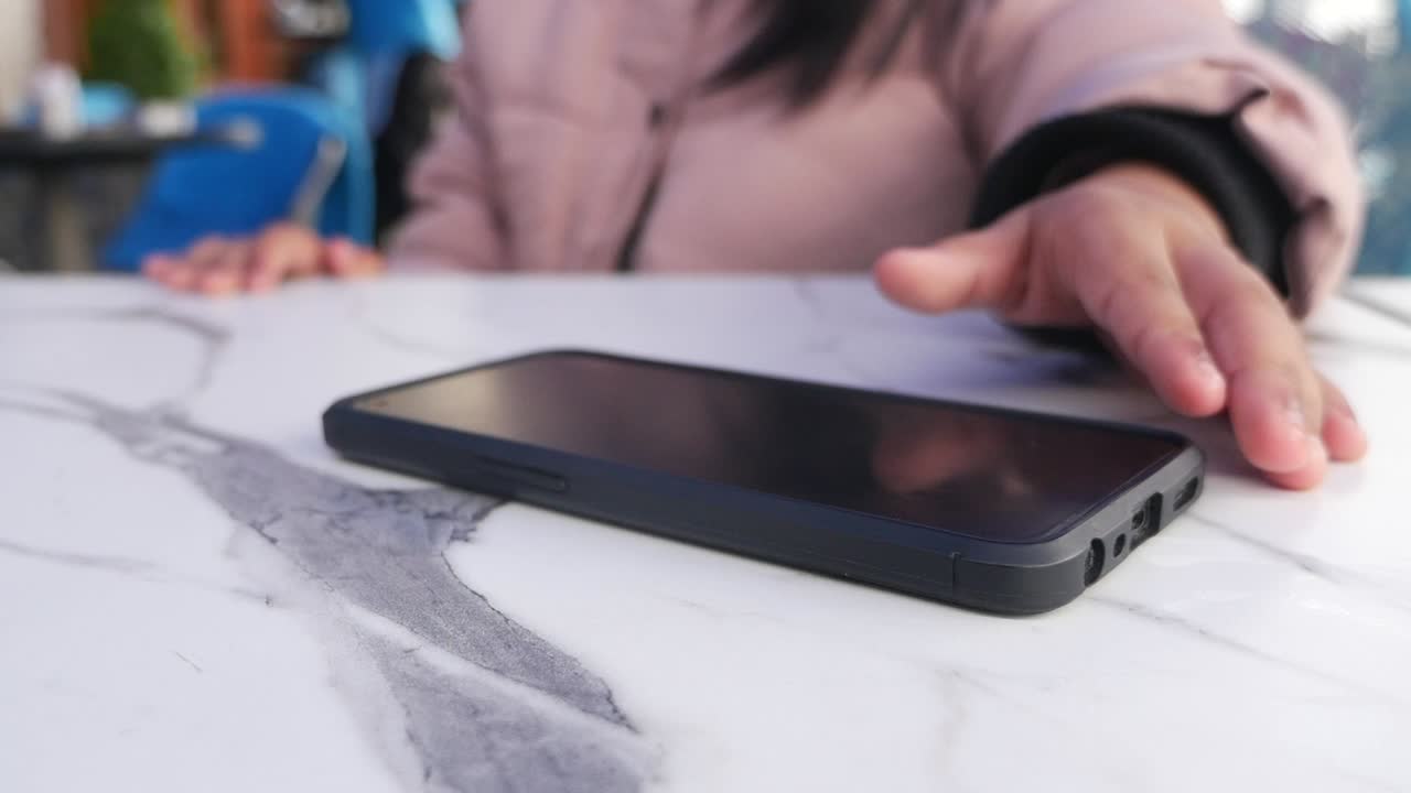 카페 테이블 에 있는 전화 를 잡으려는 여자