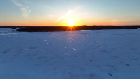 Rückwärtsflug-über-Einen-Zugefrorenen-See-Bei-Sonnenuntergang