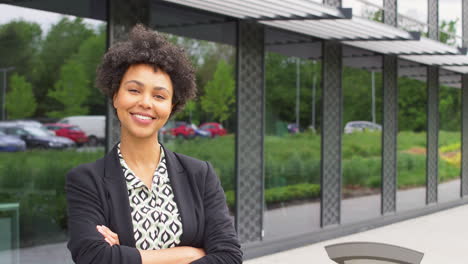 portrait of smiling businesswoman standing outside modern office building