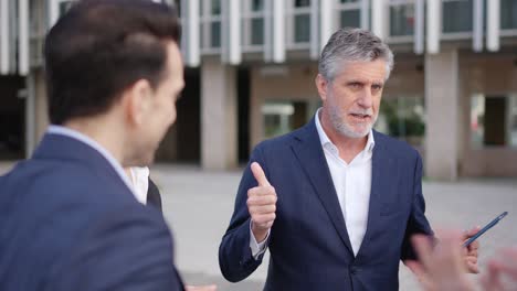 business professionals discussing outdoors with a tablet