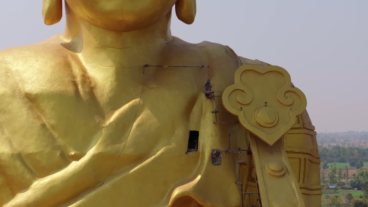 タイの都市でクレーンで建設中の巨大な黄金の仏像を映すドローン