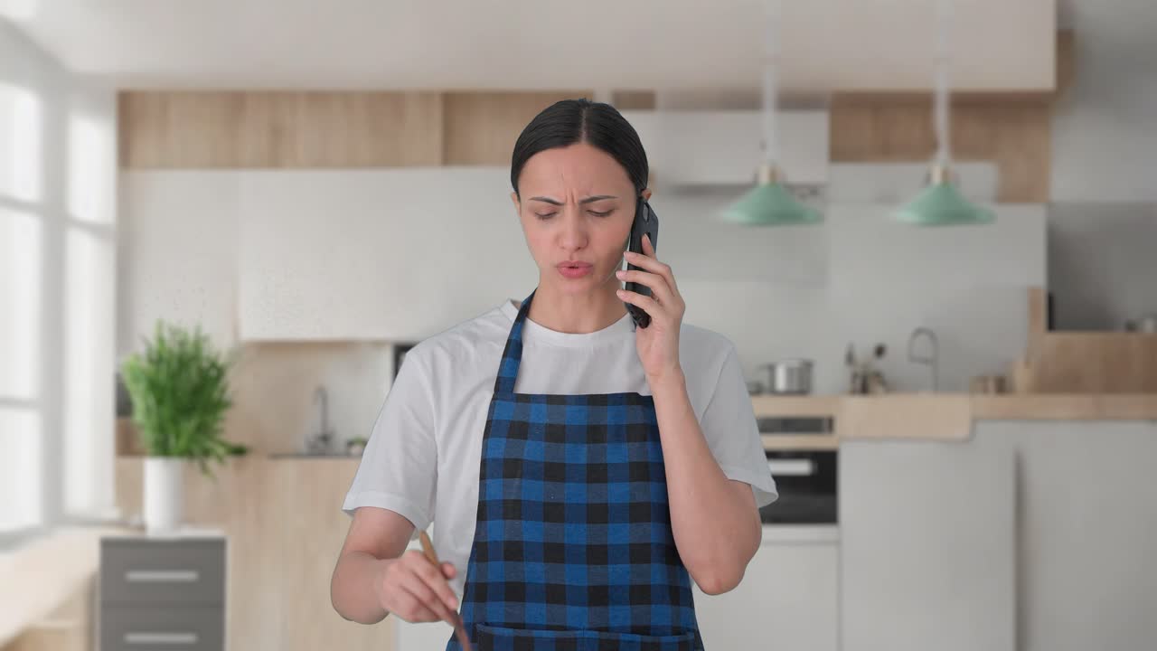 ama de casa india enojada gritando en la llamada mientras hace comida
