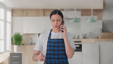 ama de casa india enojada gritando en la llamada mientras hace comida