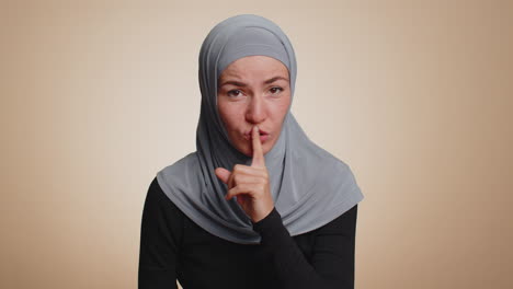 Young-woman-presses-index-finger-to-lips-makes-silence-gesture-sign-do-not-tells-secret-shh-be-quiet