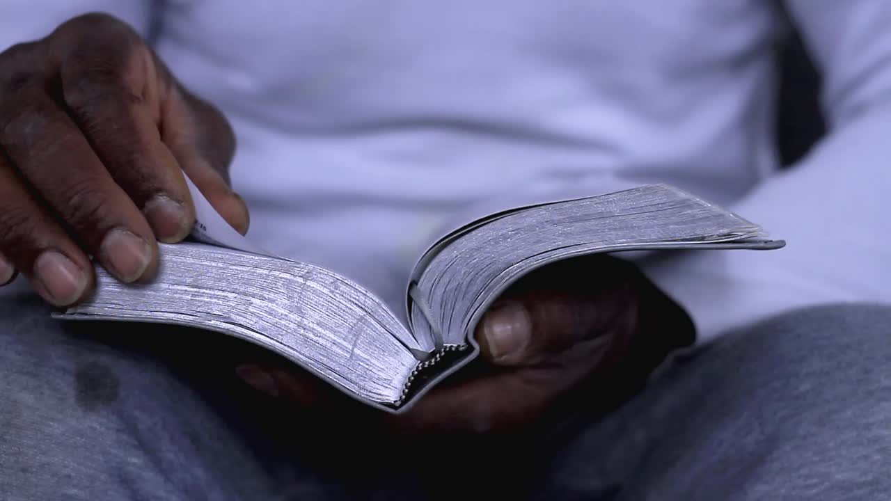 man praying to god with hands together with bible Caribbean man praying with white background stock footage