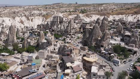 drone establishing ascends above rock valleys with homes carved out of side at midday, cappadocia turkey