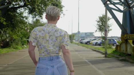 Stylish-woman-walks-confidently-through-overgrown-industrial-area