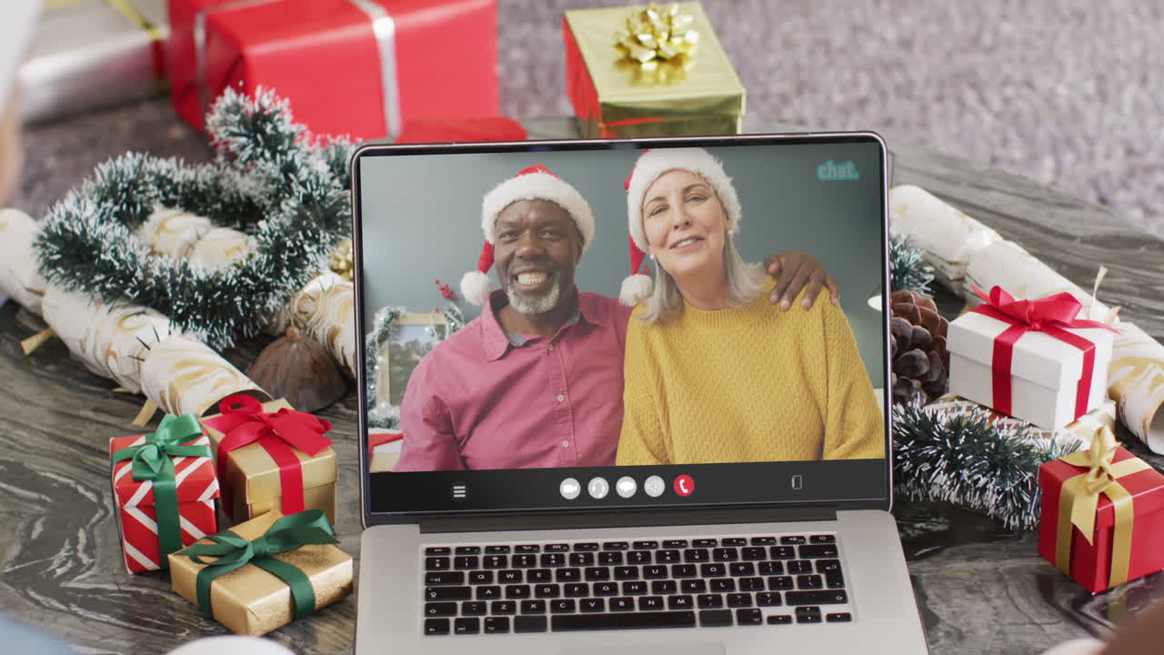 animación de una pareja diversa con sombreros de santa en una llamada de video portátil en navidad