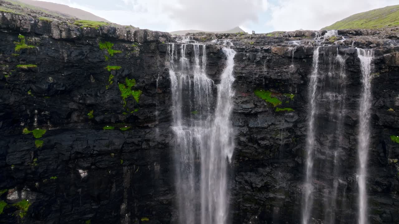 una impresionante cascada rodeada de escarpados acantilados y musgo, las islas feroe