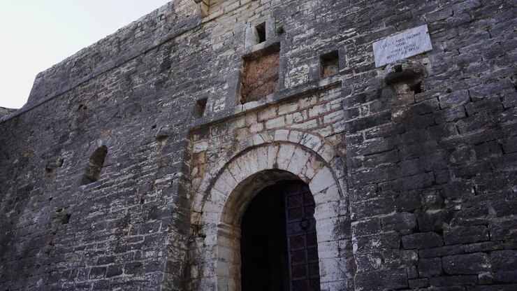 Entrada de fortaleza com muros de pedra e portão em arco de um castelo medieval na Albânia.