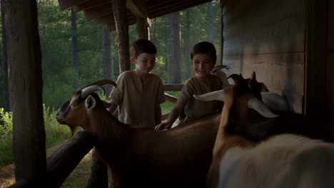 two boys petting goats in a rural setting