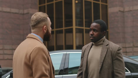 rear view of a caucasian man talking and disputing with african american man, they are arguing and one of them turning and going away