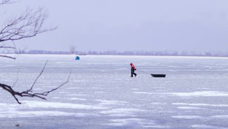 fisher men waking on frozen lake, pulling ice sledge, ice fishing, winter cold outdoor, fishing tent on frozen lake, mid shot canada wide view of landscape