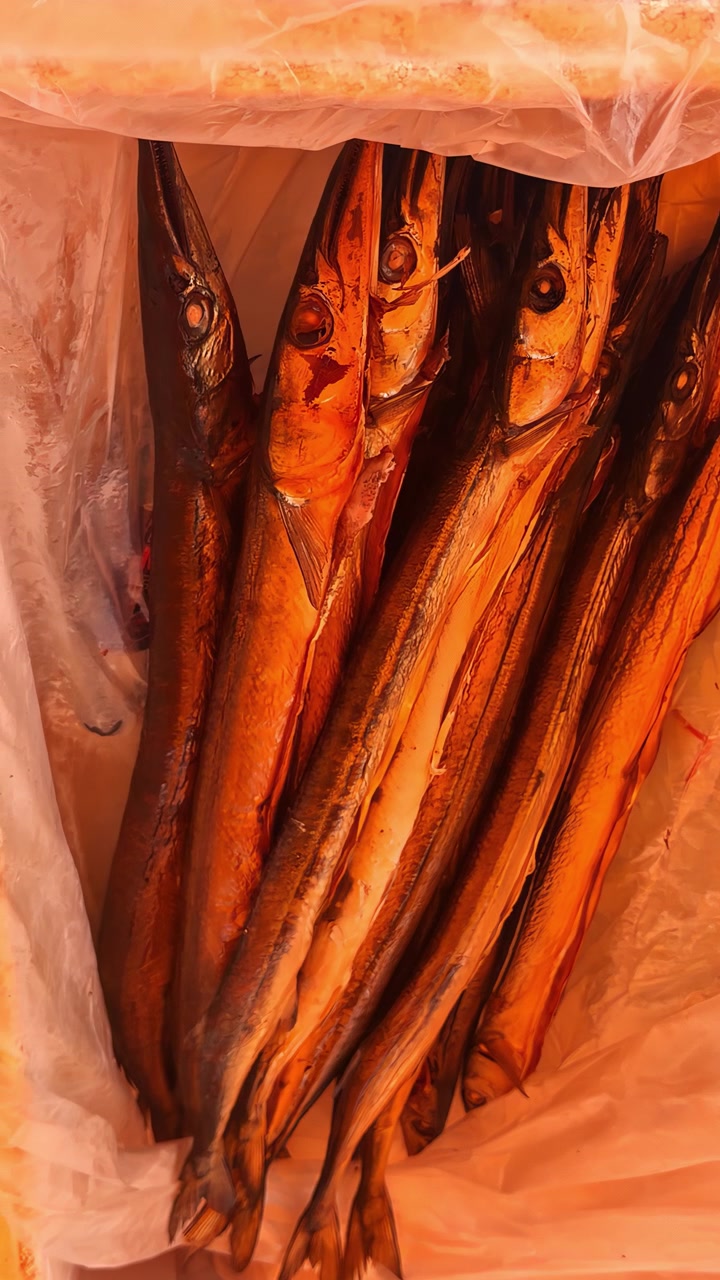 Una colorata disposizione di pesce affumicato appeso in un ambiente di mercato, che mostra ricche texture e tonalità.