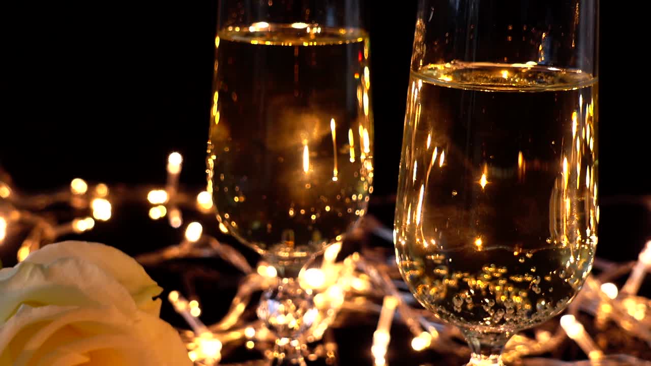 Calici da champagne e una rosa sullo sfondo di ghirlande luminose