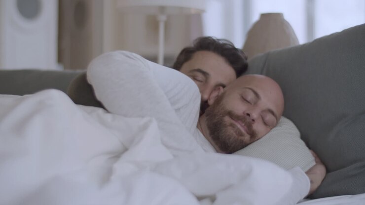 Homoseksuelt par, der ligger under et tæppe om morgenen og krammer