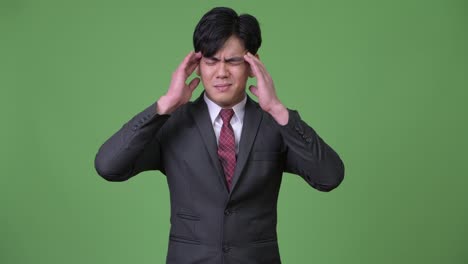 stressed young handsome asian businessman having headache