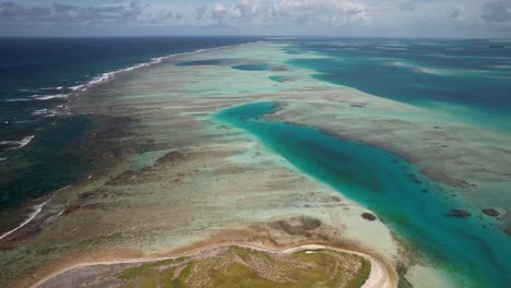 Cayo-de-agua-in-los-roques,-revealing-striking-turquoise-waters-and-coral-reefs,-aerial-view