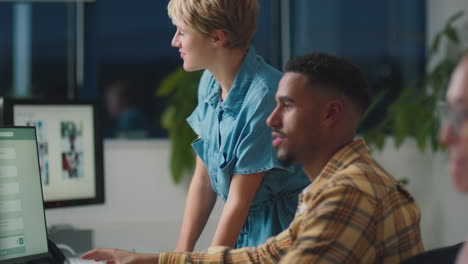 two business colleagues at desks in office working late on project together