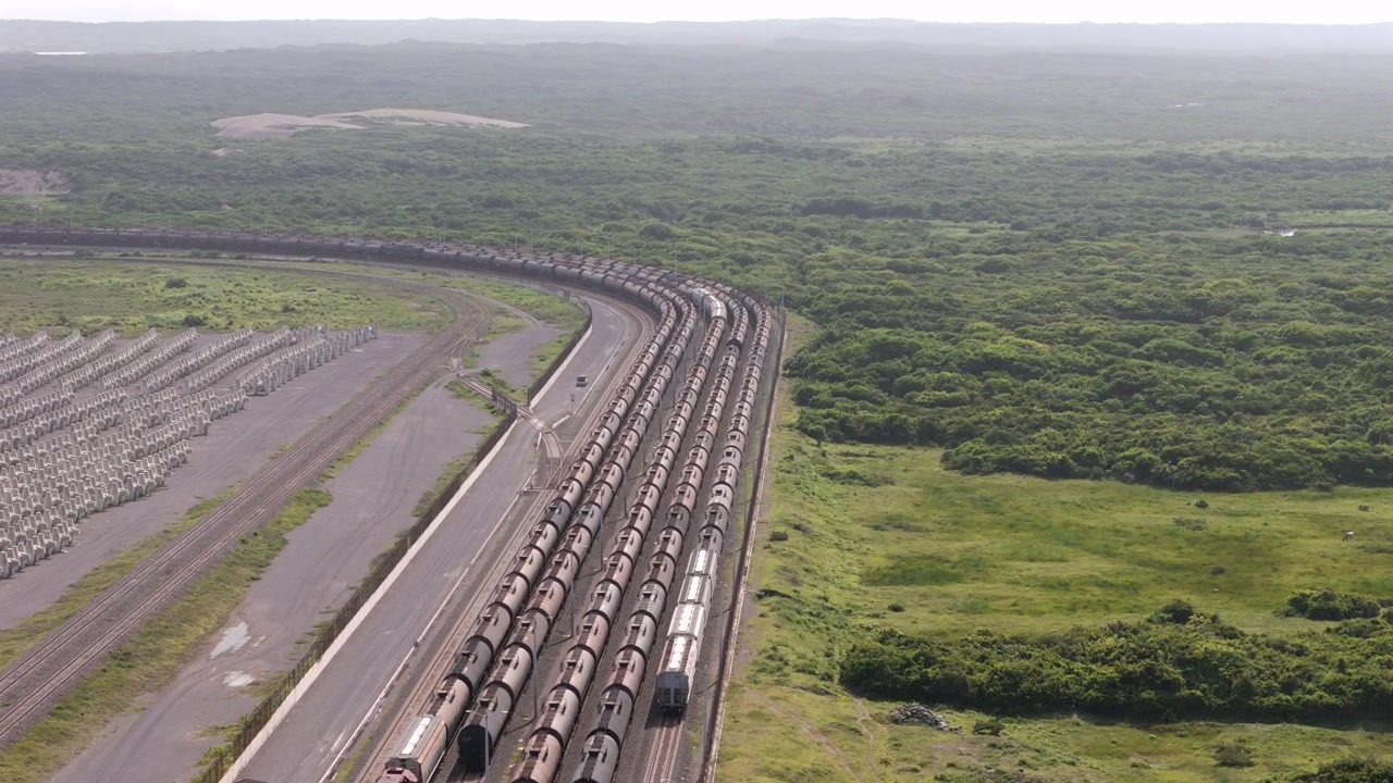 Barisan panjang gerbong kereta barang di lahan pesisir hijau dekat Pelabuhan Veracruz, dari udara