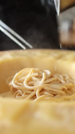 chef preparing creamy cheese pasta in a wheel of parmesan