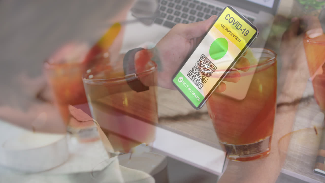 화면에 코비드 여권과 함께 스마트폰을 들고 있는 백인 남자의 손 위에 음료의 애니메이션