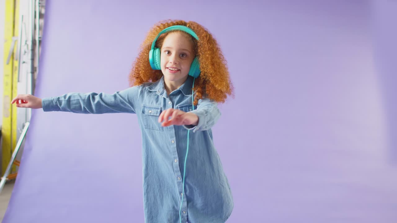 Studio shot of girl with headphones dancing and flossing against purple background - shot in slow motion