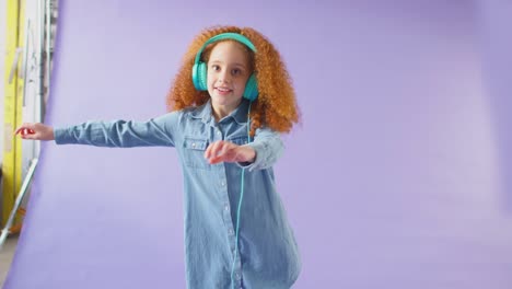 studio shot of girl with headphones dancing and flossing against purple background - shot in slow motion