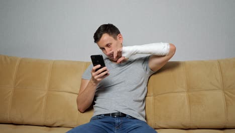 hombre moreno pega la nariz con el brazo roto desplazándose por las redes sociales