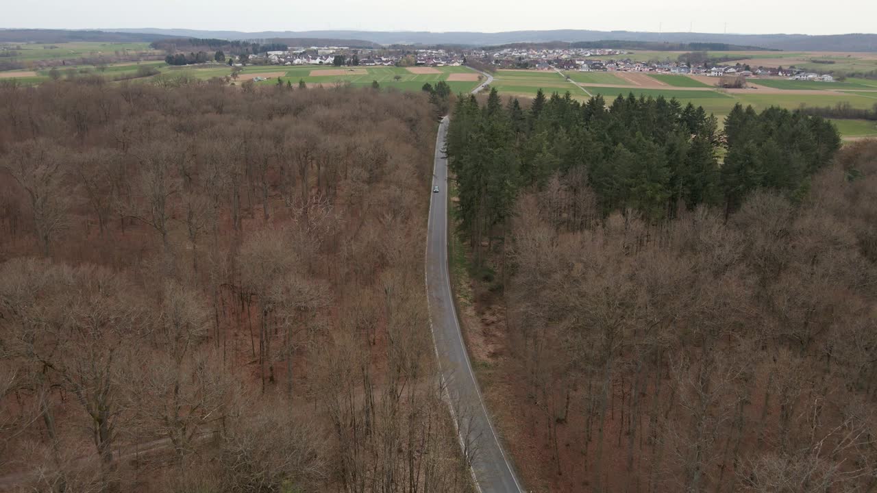 Approccio aereo verso un'autostrada di campagna deserta con un'auto in arrivo che esce dall'inquadratura