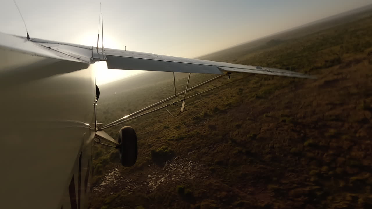 Small air plane side view over dry grassy shrubs