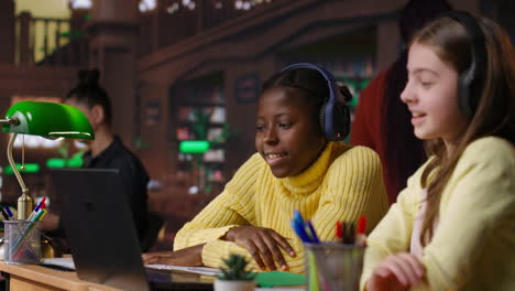 two girls studying together on laptop in a library setting