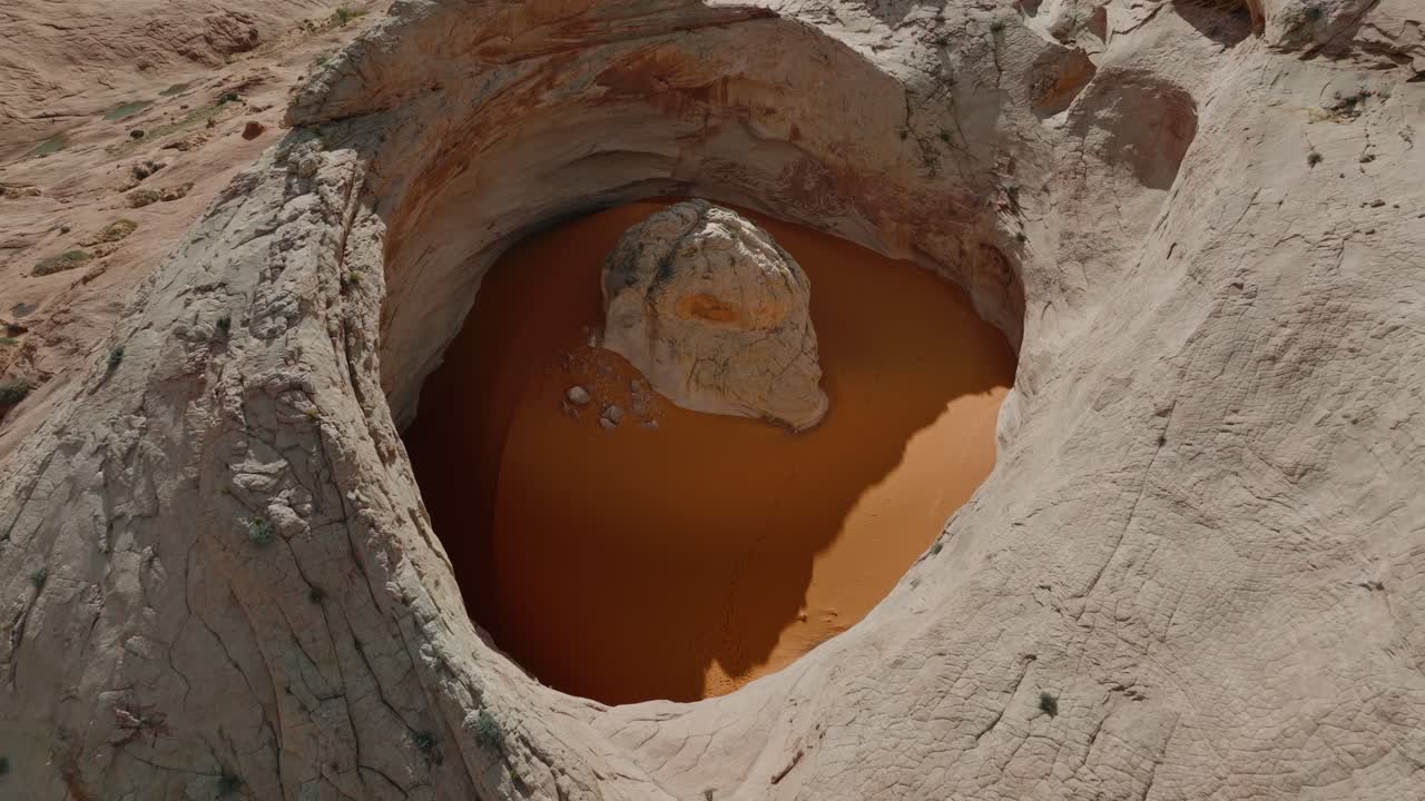Ripresa aerea ravvicinata del bacino roccioso Cosmic Ashtray con una pozza di sabbia arancione nel deserto dello Utah, drone.