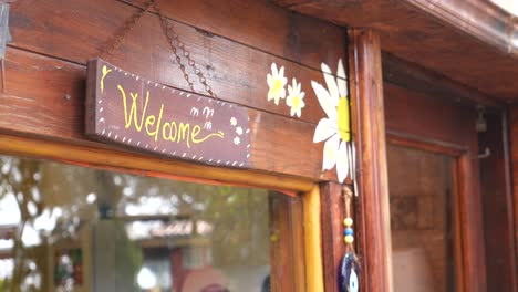 close-up of a rustic wooden door with a welcome sign and painted flowers