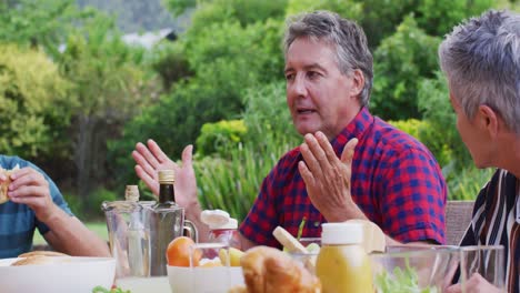 caucasian senior man talking during family celebration meal in garden