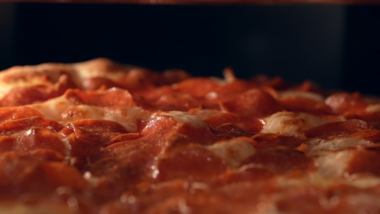 고르게 굽기 위해 오븐에서 페퍼로니 피자를 돌리기 - 격리된 보기를 닫습니다.