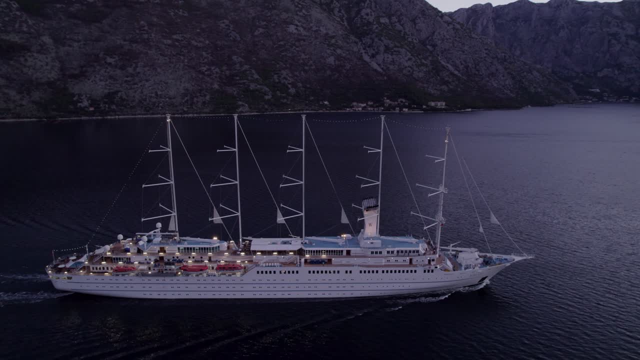Ilmakuva purjealuksesta Kotorinlahdella auringonnousun aikaan Kotorissa, Montenegro, upeassa auringonnousun valossa, rauhallinen tunnelma, korkealaatuista dronekuvaa esitellen kauniita maisemia