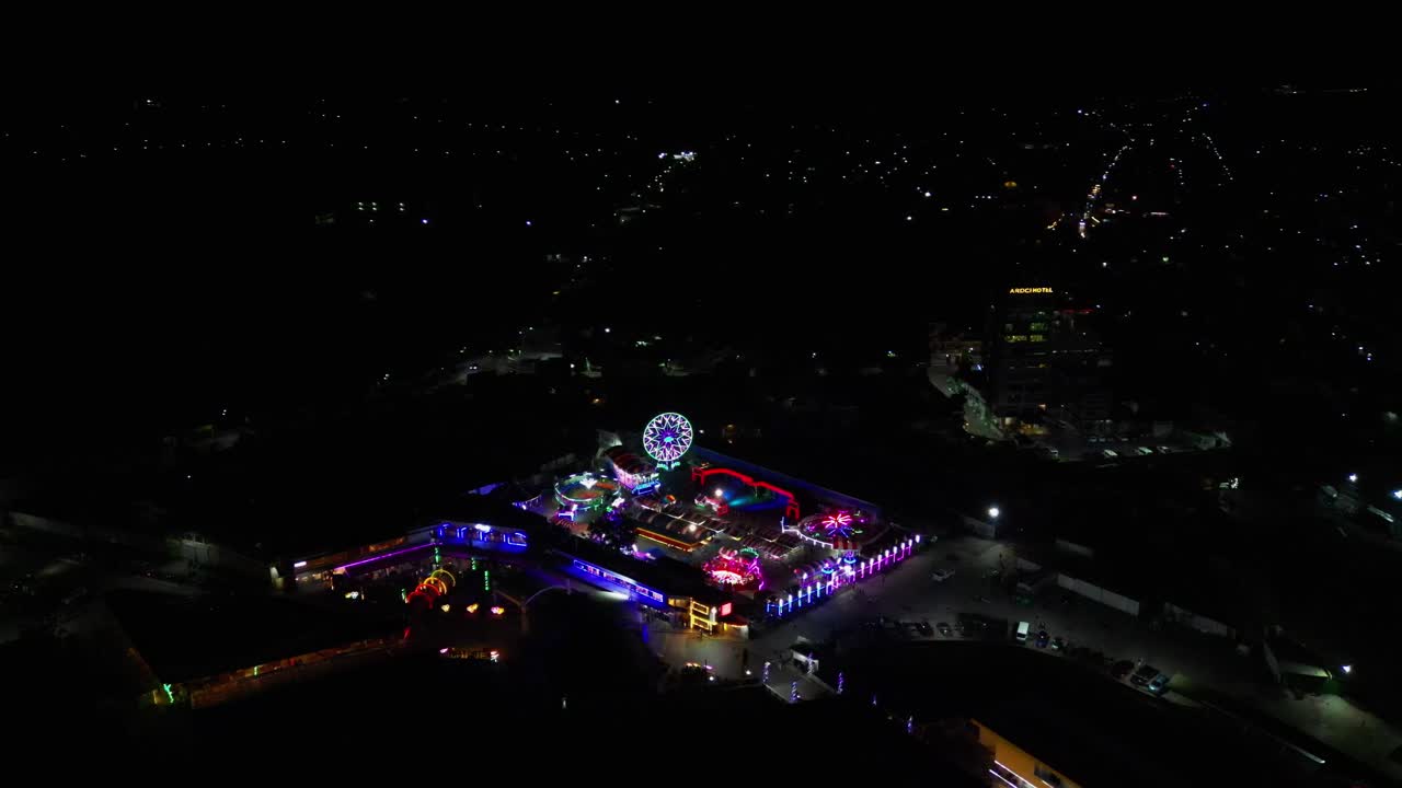 Orbiting aerial view of colorful festival pop-up carnival and amusement park caravan during night at Virac, Catanduanes, Philippines