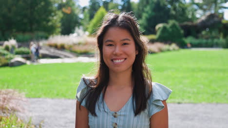 beautiful young adult asian girl smiling looking at camera in garden