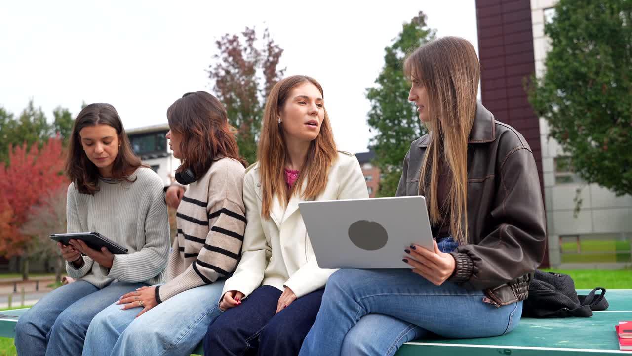 Fire unge kvinder studerer og diskuterer udendørs på campus