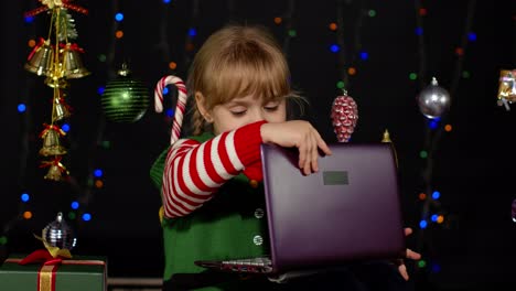 Niña-Vestida-De-Elfo-Navideño-Haciendo-Compras-En-Línea-Usando-Una-Computadora-Portátil,-Navegando-En-Las-Redes-Sociales